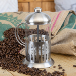 A glass cafetiere with a silver case, lid and handle.